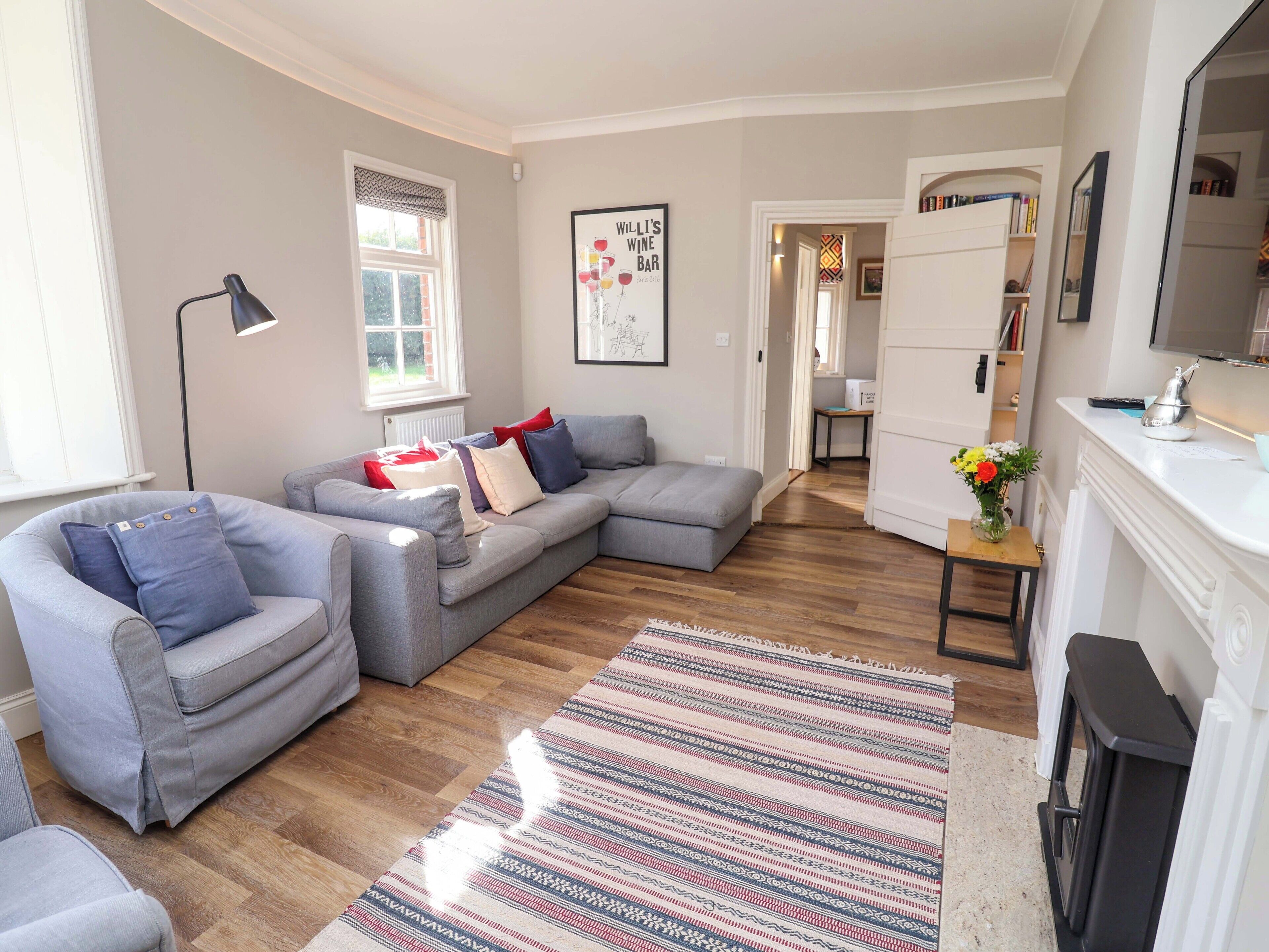 A modern living room with a grey sectional sofa, a small table with a vase of flowers, and a patterned rug.