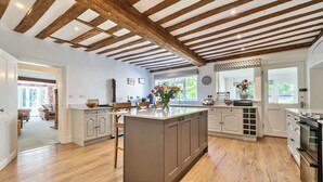 Une cuisine moderne avec des poutres en bois, un îlot central et une vue sur l’extérieur.