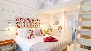 Une chambre à coucher avec un lit, une table de chevet, un miroir et une vue sur l’étage supérieur.