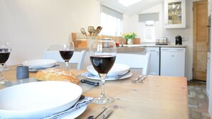 Una mesa de comedor con platos, copas de vino tinto, un pan y cubiertos.