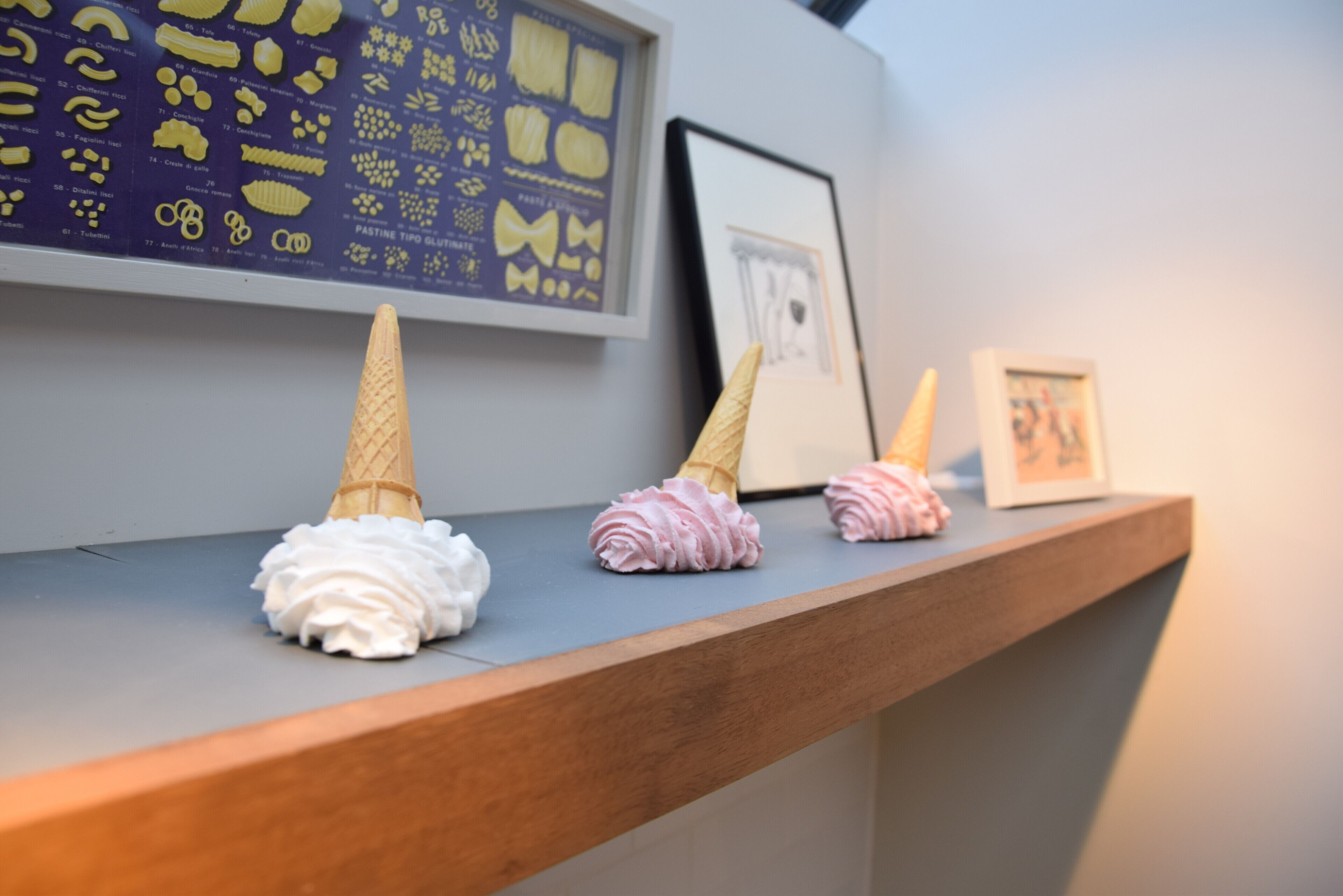 Una composizione di coni gelato con diversi condimenti su un ripiano di legno.