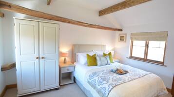 A bedroom with a large wardrobe, a bed with a patterned bedspread, and a window with a curtain.