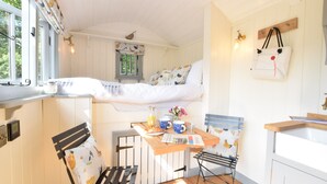 A compact kitchen with a wooden table, a bench, and a small window.