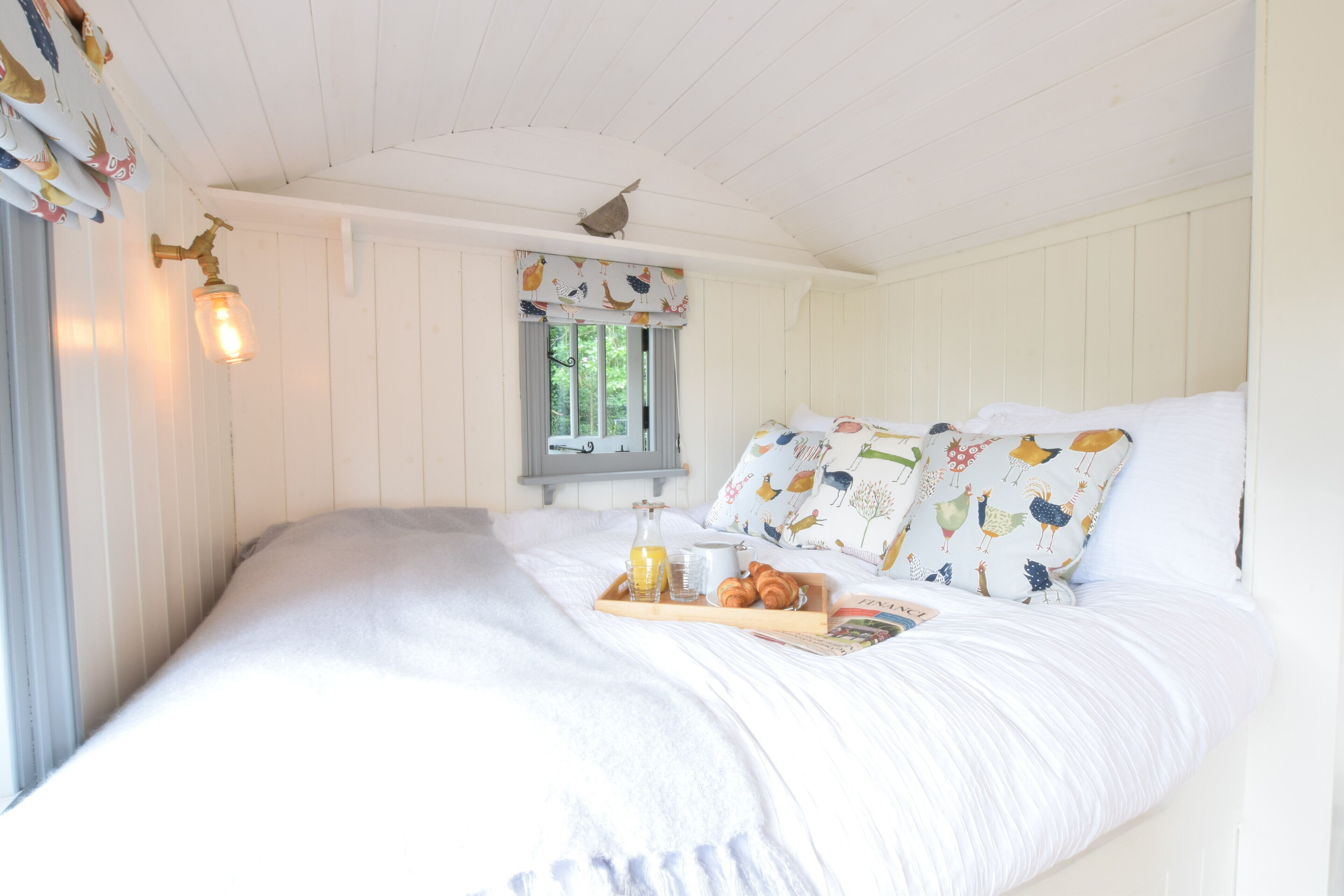 A bed with white bedding, a tray with breakfast items, and a window with curtains.