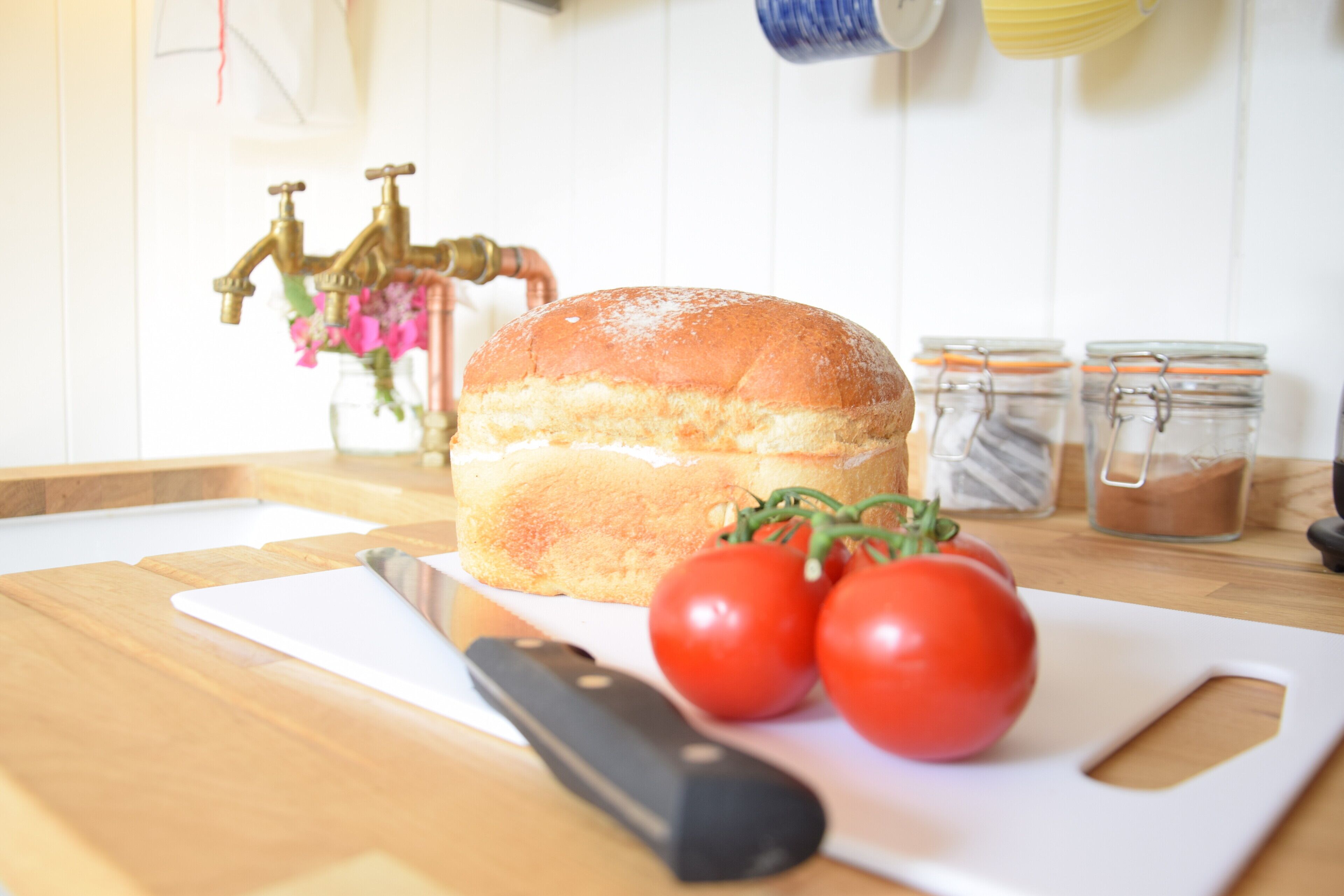 Una encimera de cocina con pan, tomates y un cuchillo.