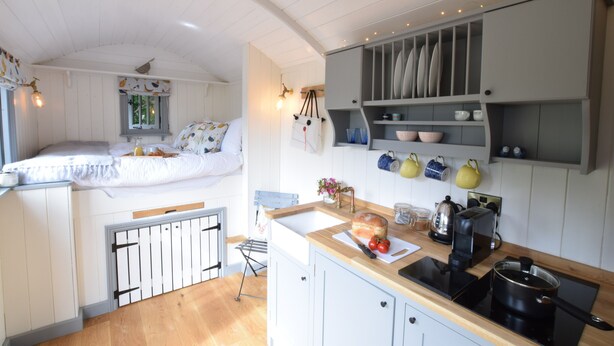 A compact kitchen with a wooden countertop, a built-in oven, and a small dining area with a bench.