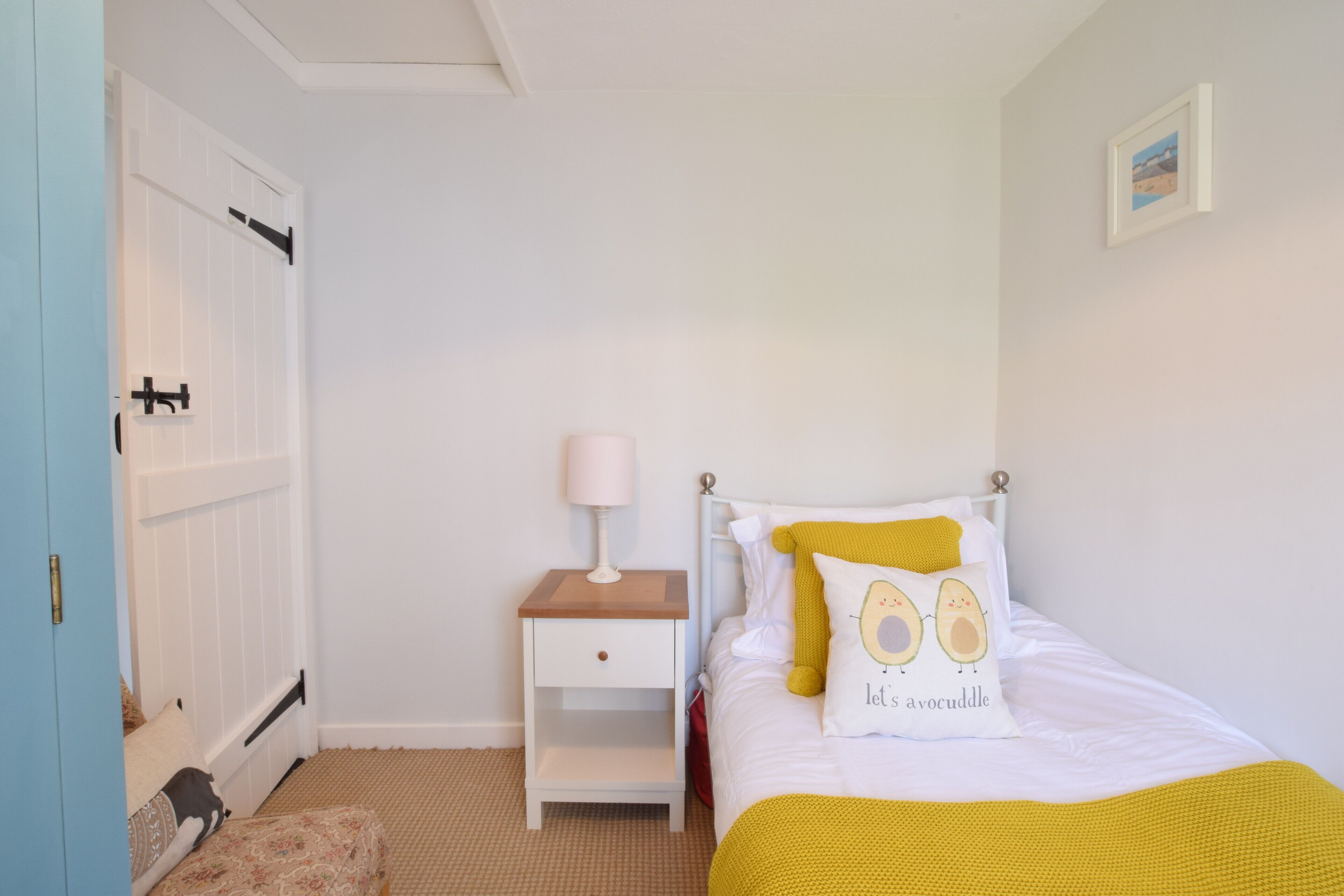 A bedroom with a bed, a nightstand, a lamp, and a door.