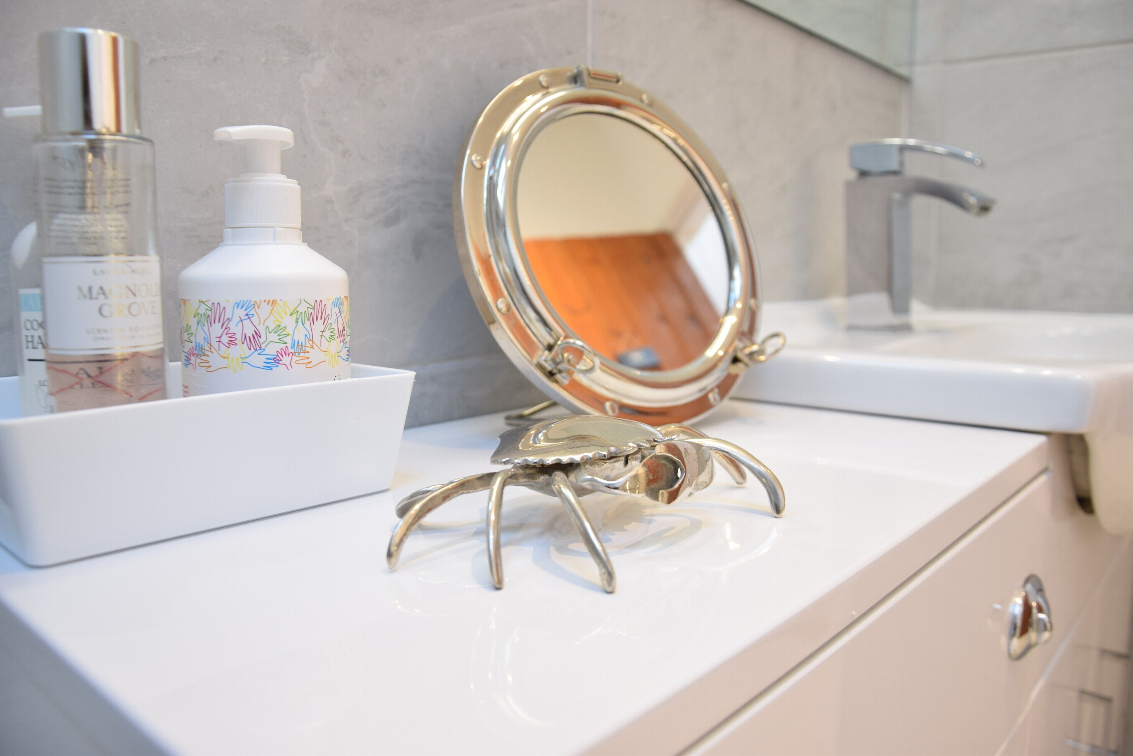 Un mobile bagno con specchio, lavandino e due flaconi di sapone per le mani.