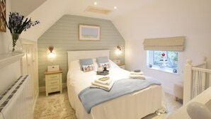 Un dormitorio con cama, mesitas de noche, un velador, una ventana con cortinas y un cuadro colgado en la pared.