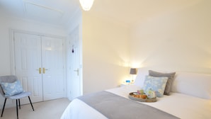 A bedroom with a bed, bedside table, lamp, and a chair. - Bluebelle Cottage, Peasenhall (Saxmundham)