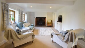 A living room with two sofas, a fireplace, a TV, and a window with curtains. - Skelder, Parham (Woodbridge)