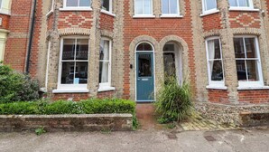A corner house with a blue door, multiple windows, and a brick facade. - 14 Dunwich Road, Southwold (Reydon)