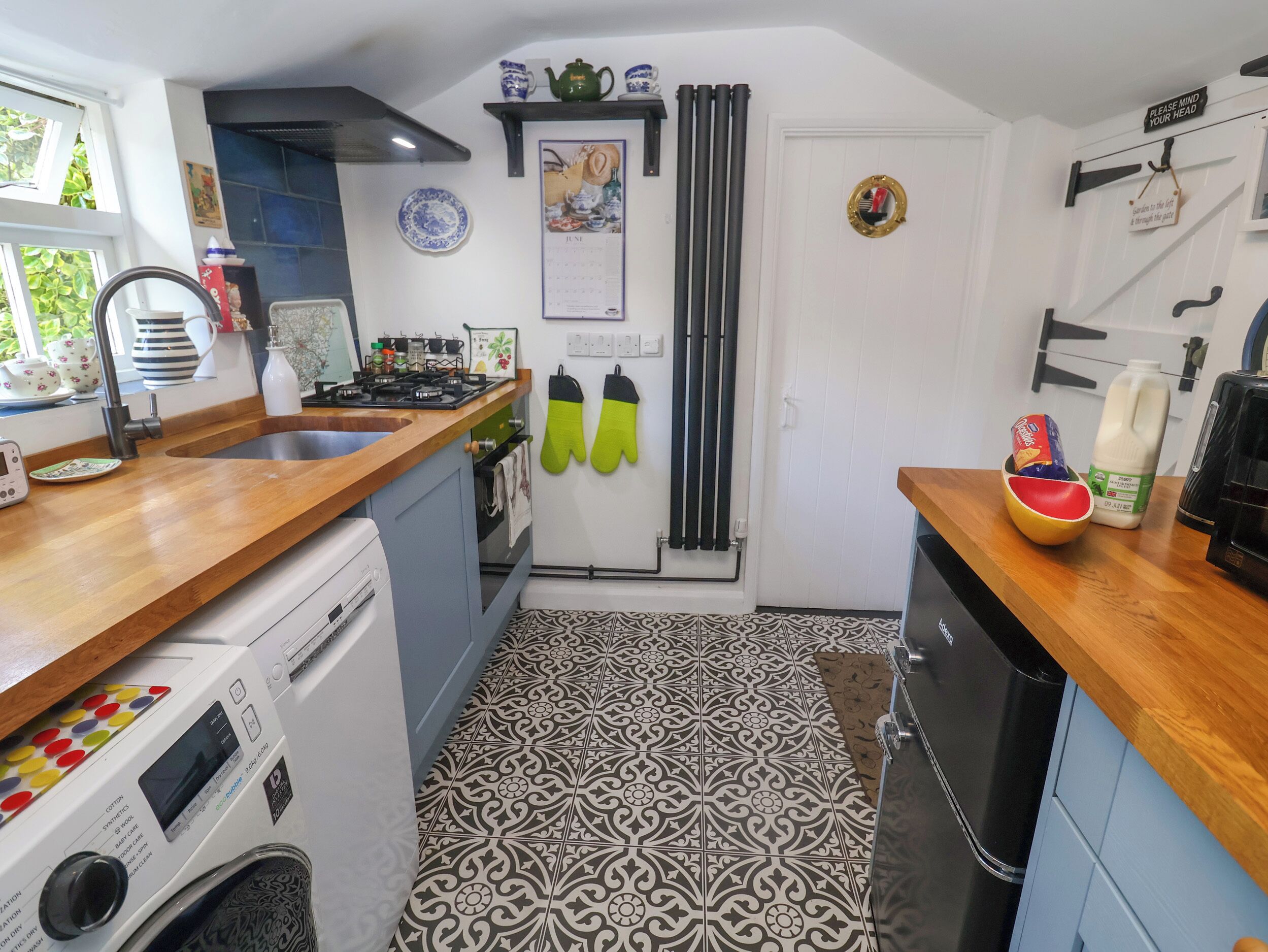 A compact kitchen with a washing machine, a stove, and a refrigerator.