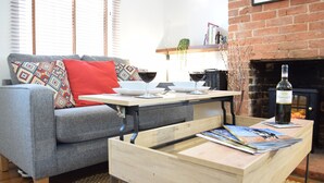 A living room with a grey sofa, a wooden coffee table, and a fireplace.