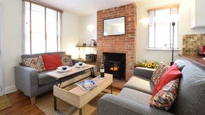 A living room with a fireplace, a sofa, a coffee table, and a bookshelf.