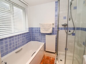 A bathroom with a bathtub, a shower, and a window with blinds. - Cobblers Cottage, Southwold (Reydon)