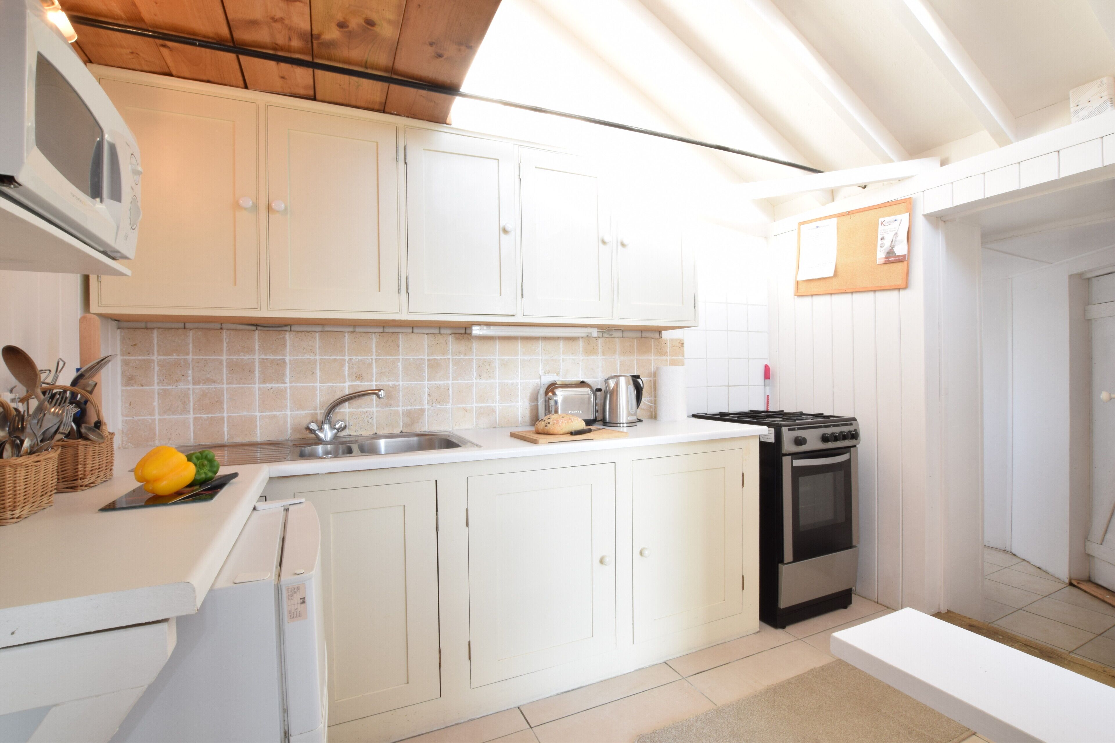 A kitchen with white cabinets, a microwave, a stove, and a sink.