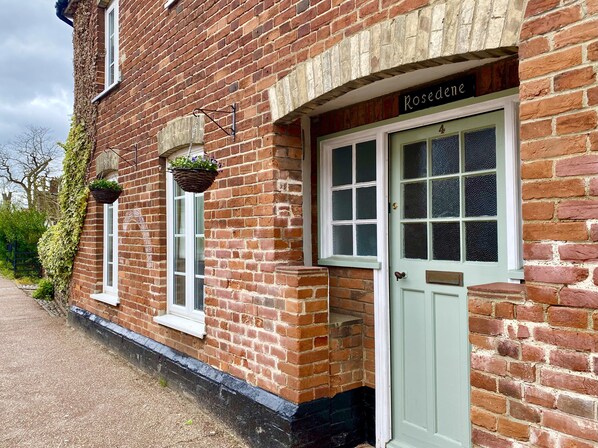 Un edificio de ladrillo con una puerta verde que dice 'Rosedene'.
