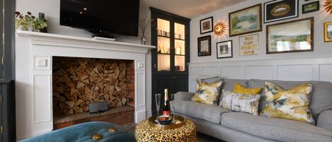 A living room with a fireplace, a sofa, a television, and various framed pictures on the wall.