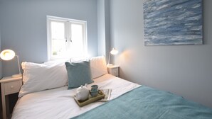 A bedroom with a bed, bedside tables, a window, and a painting on the wall. - 15 Victoria Street, Southwold (Reydon)