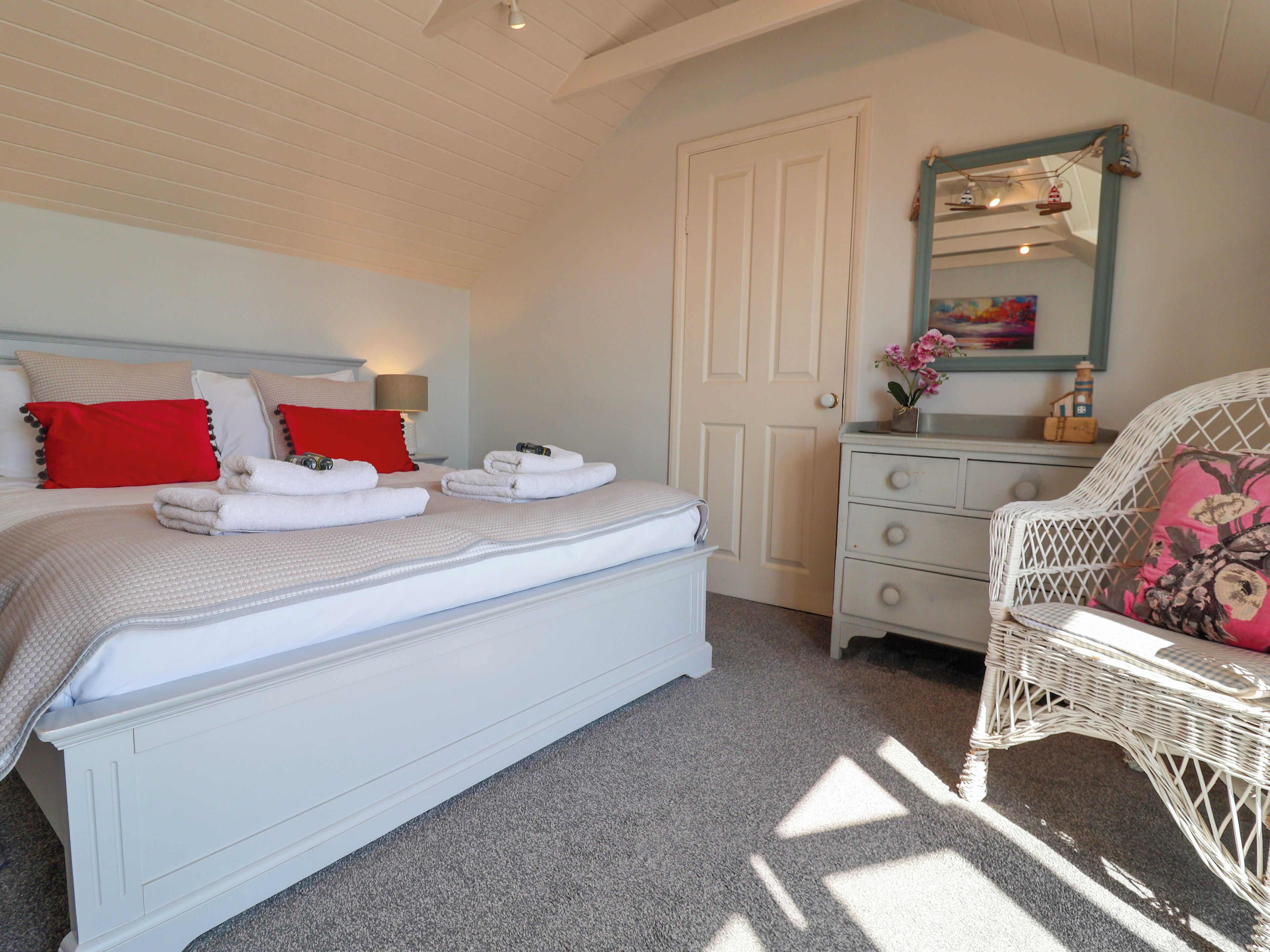 A bedroom with a bed, a dresser, a chair, and a door.