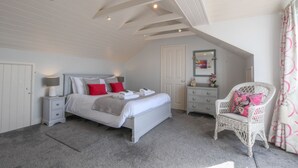 Een slaapkamer met een bed, nachtkastjes, een stoel en een plafond met zichtbare balken.
