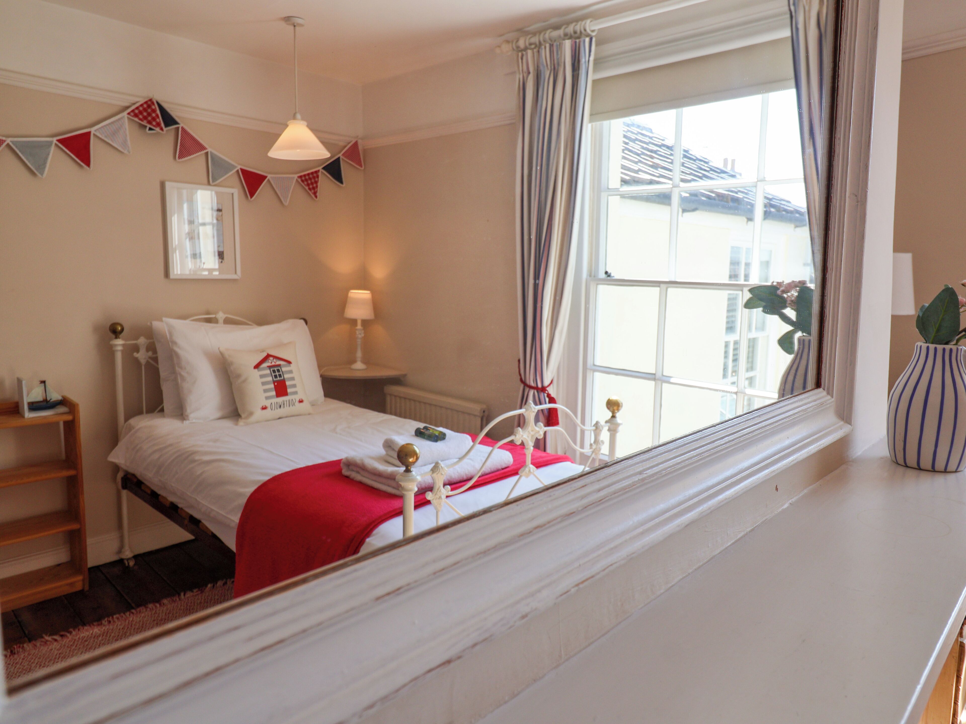 Een slaapkamer met een bed, nachtkastje, lamp en een raam met gordijnen.