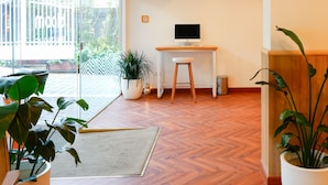 A modern office space with a wooden herringbone floor, a desk with a computer, and potted plants. - Bloom Boutique - Bandra (Mumbai)