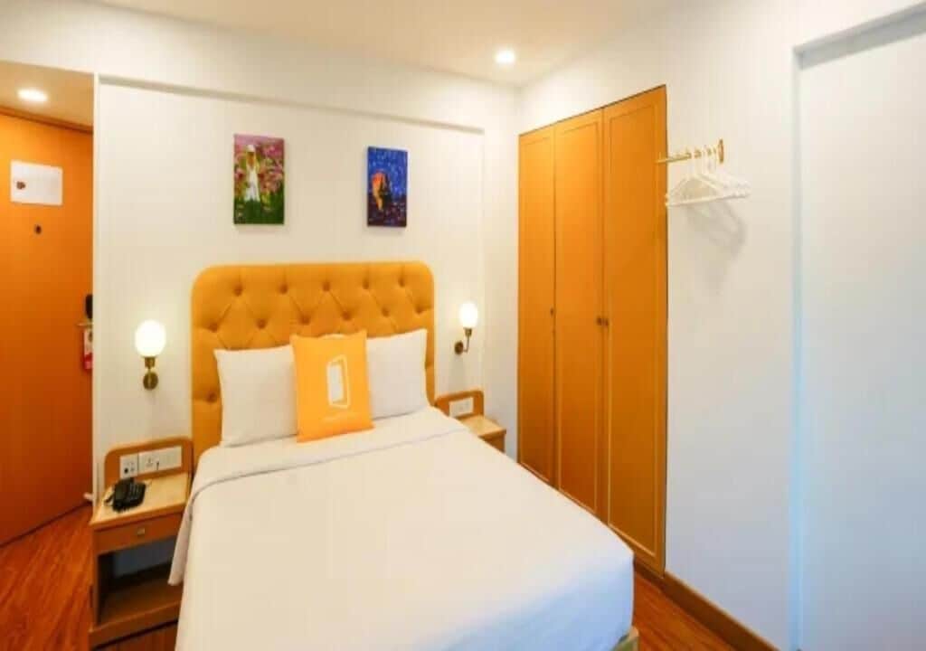 Habitación de hotel con cama, mesitas de noche, un armario y dos cuadros colgados en la pared.