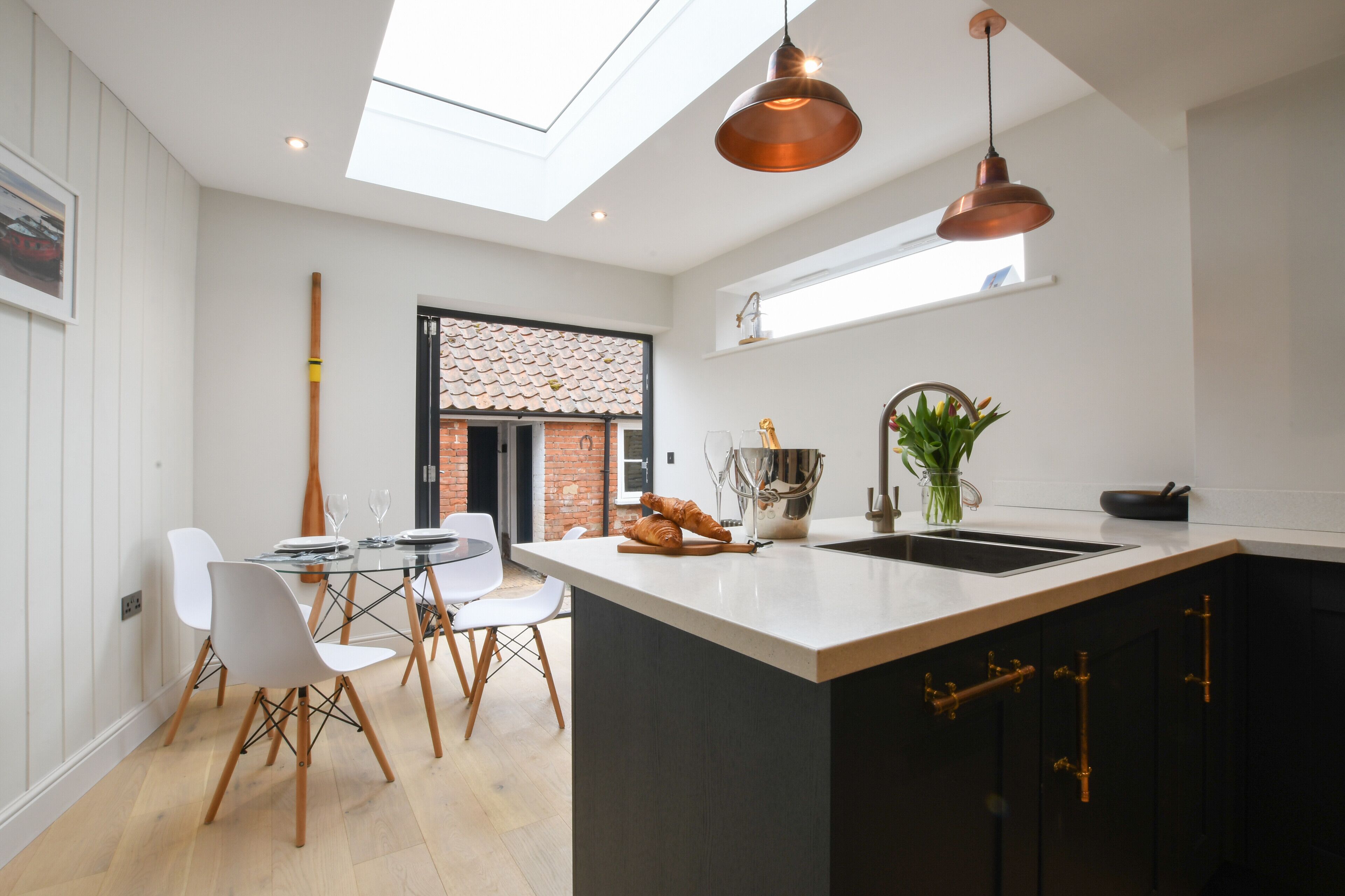 A modern kitchen with a central island, white cabinetry, and copper pendant lighting.