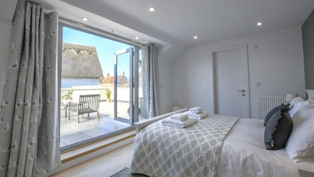 Une chambre avec une grande porte-fenêtre coulissante donnant sur un balcon, un lit avec des oreillers et un radiateur.