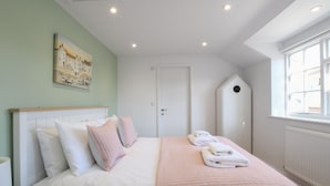 Une chambre à coucher bien rangée, avec un lit, des oreillers, une couverture matelassée et une serviette pliée posée sur le lit.
