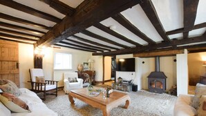 A cozy living room with exposed wooden beams, a fireplace, a television, and comfortable seating. - Church Farmhouse, Cookley (Halesworth)