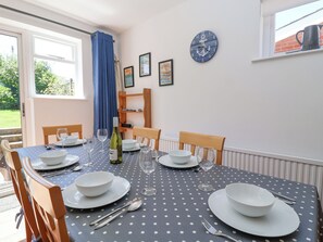 A dining area with a table set for four, featuring a polka dot tablecloth, white plates, bowls, and cutlery.