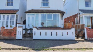 A two-story house with a white facade, a tiled roof, and a gated entrance. - Time Out, Southwold (Reydon)