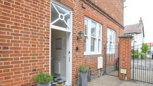 A brick house with a white door, a black and white checkered floor, and a black metal gate. - 1 Eversley Court, Southwold (Reydon)