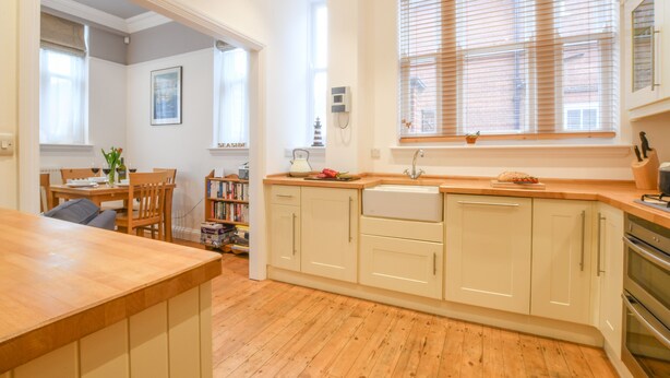 A kitchen with wooden cabinets, a sink, and a window with blinds. - 1 Eversley Court, Southwold (Reydon)