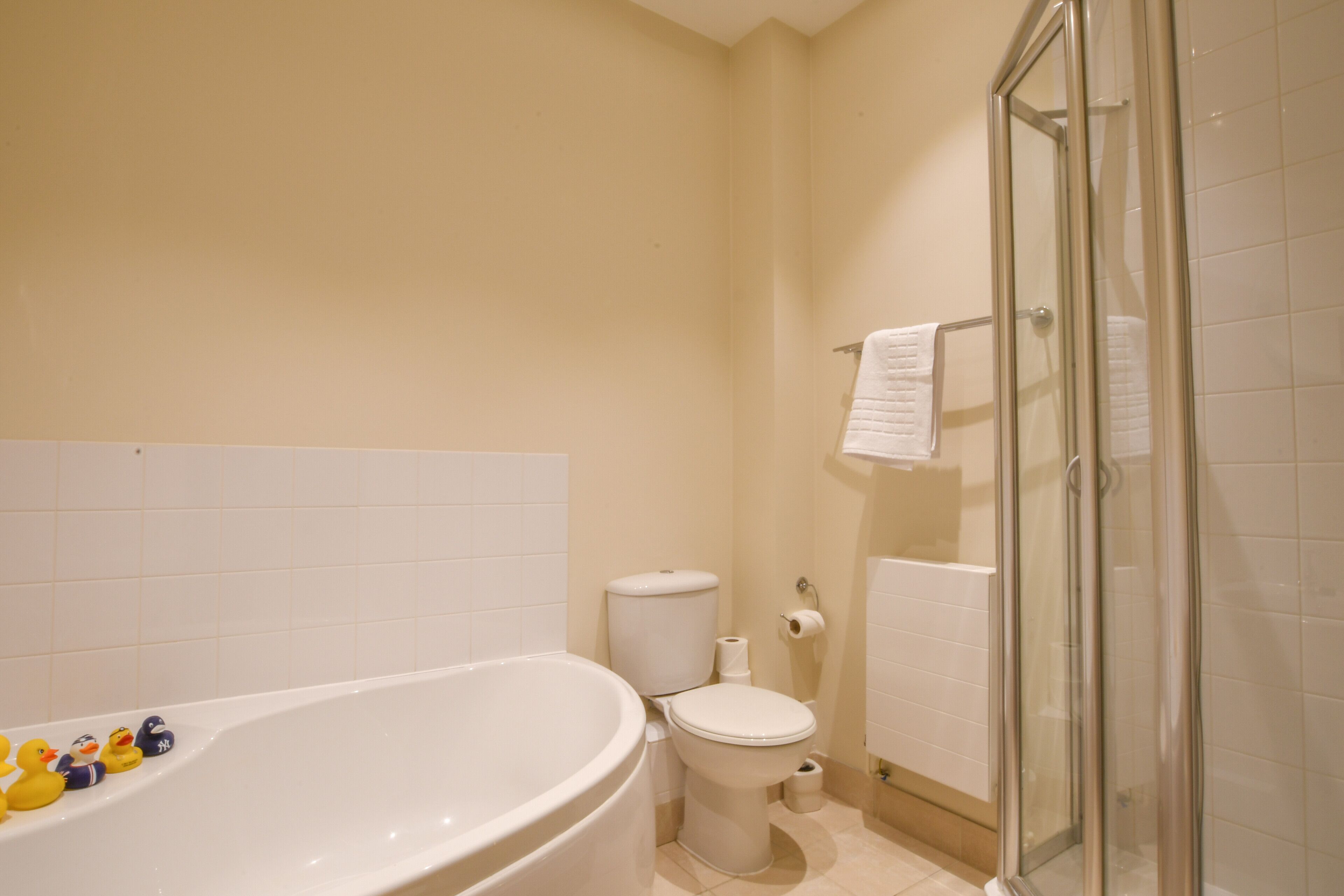 A bathroom with a bathtub, toilet, and glass shower enclosure.