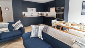 Una sala de estar moderna con un sofá y una mesa de comedor lista para el desayuno.