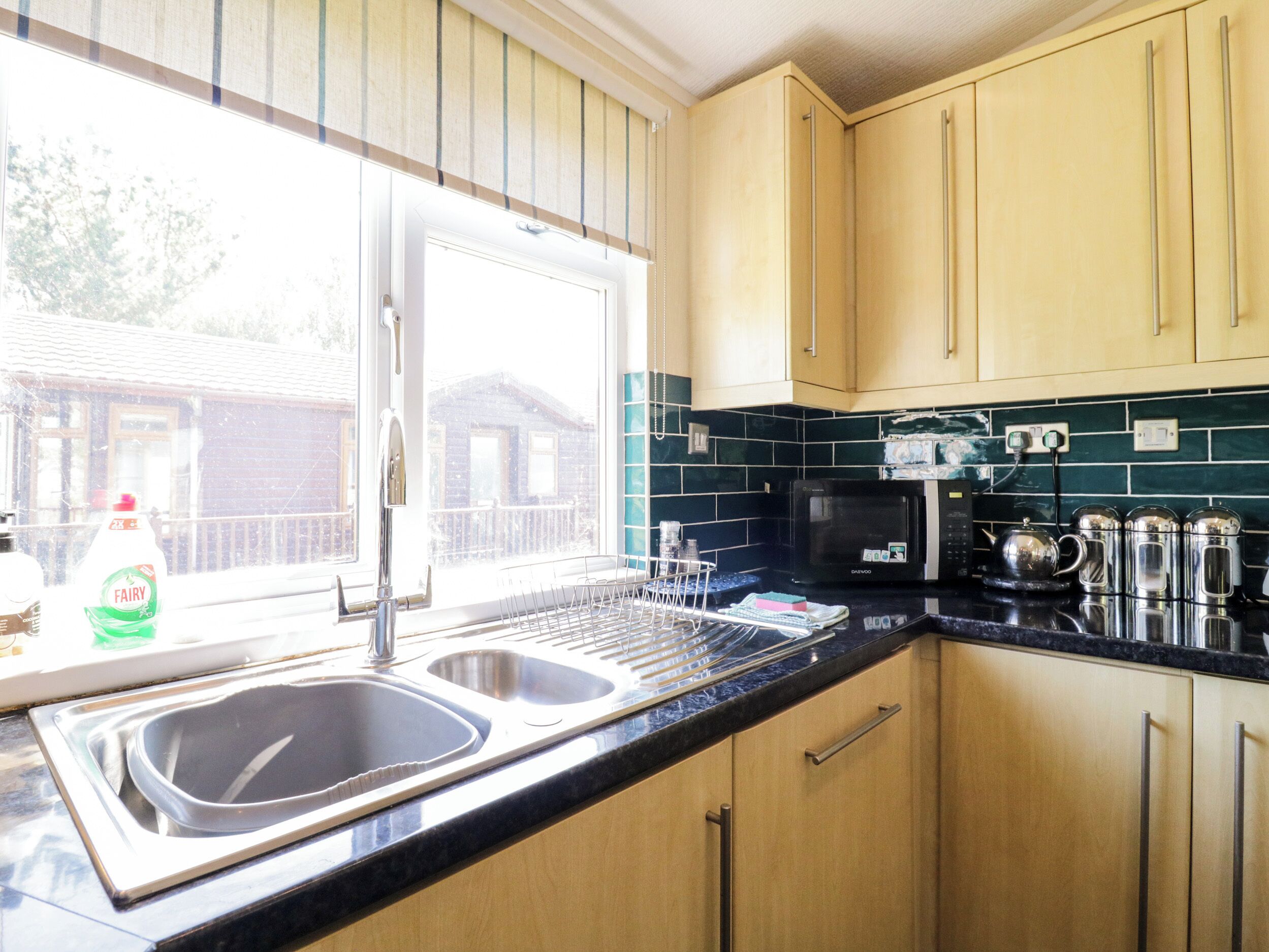 A kitchen with two sinks, a microwave, and wooden cabinets.
