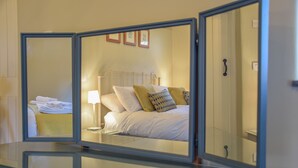 A hotel room with a bed, a nightstand, and a mirror reflecting the room. - Halcyon Barn, Wissett (Halesworth)