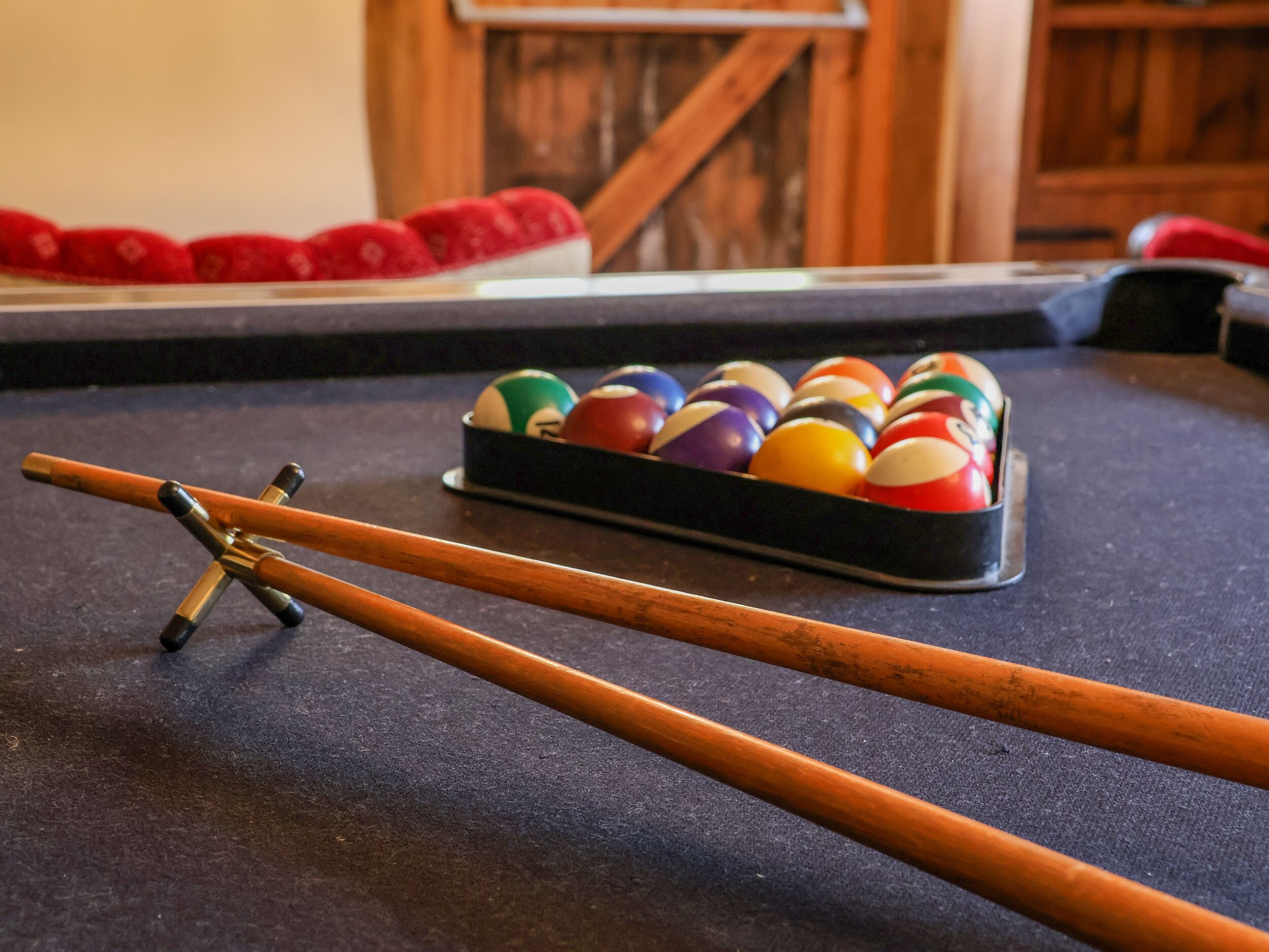 Une table de billard avec un jeu de queues de billard et un porte-billes.