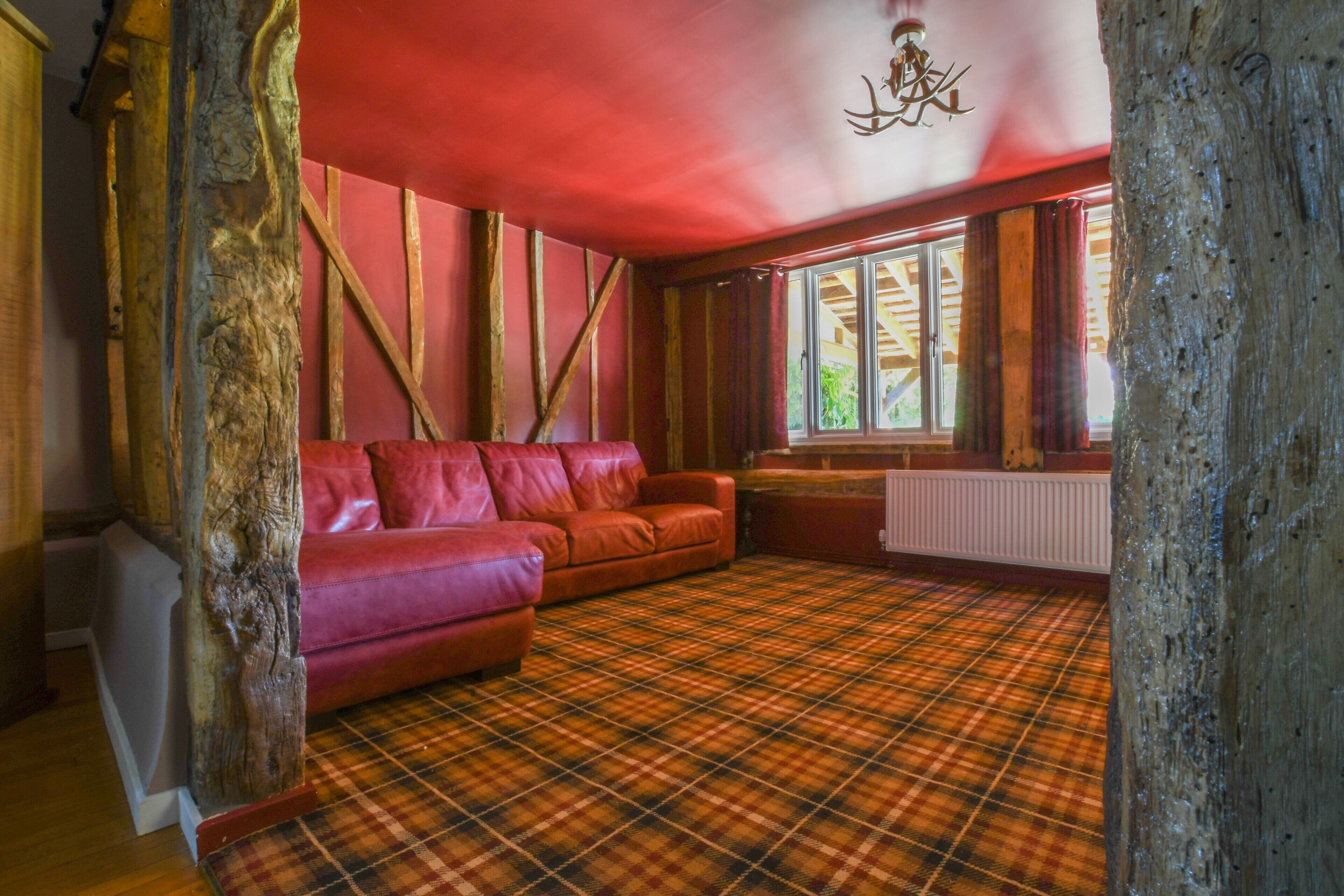 A room with a plaid carpet, red walls, and a red sofa.