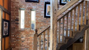 Una scala con balaustre in legno e un muro di mattoni con opere d'arte incorniciate.