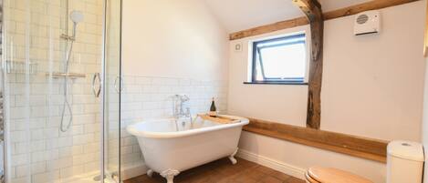 A bathroom with a glass-enclosed shower, a freestanding bathtub, and a wooden toilet.