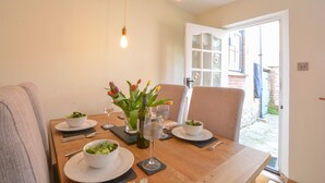 Une table à manger dressée avec des assiettes, des bols, des couverts et un vase de fleurs.