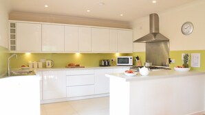 Une cuisine moderne avec des armoires blanches, une hotte de cuisinière en acier inoxydable, un four à micro-ondes et un évier.