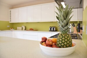 A kitchen with white cabinets, a bowl of fruit, and a pineapple on the counter. - Peach House, Aldeburgh (Aldeburgh)