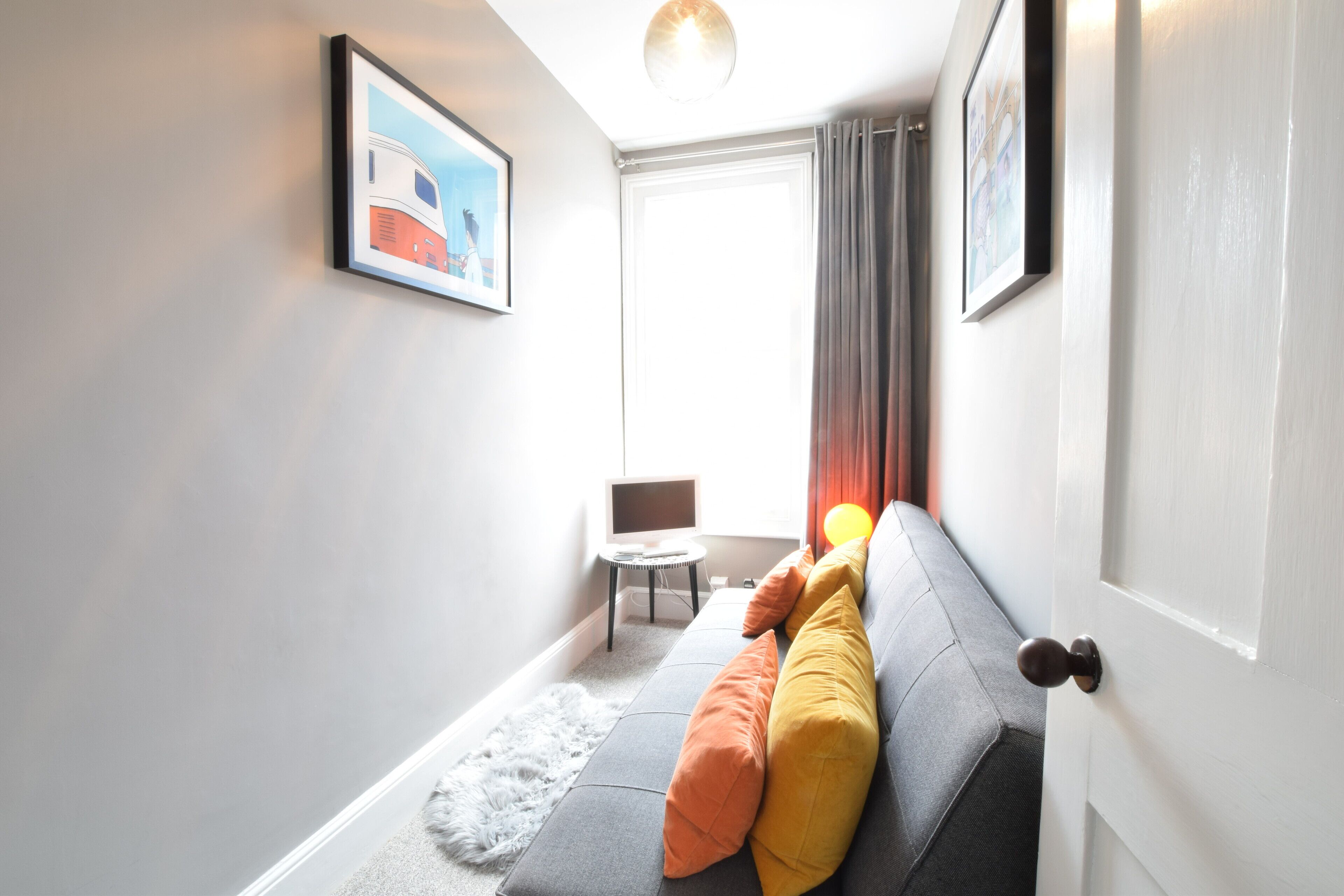 A modern living room with a grey sofa, a small round table, and a television.