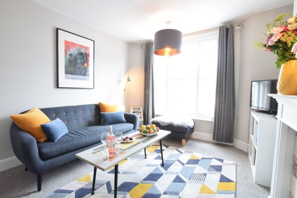 A modern living room with a sofa, coffee table, and a TV on a stand. - Driftwood, Southwold (Reydon)
